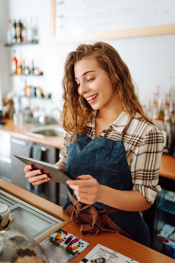 Titolare di un bar sorridente con il tablet dietro al bancone